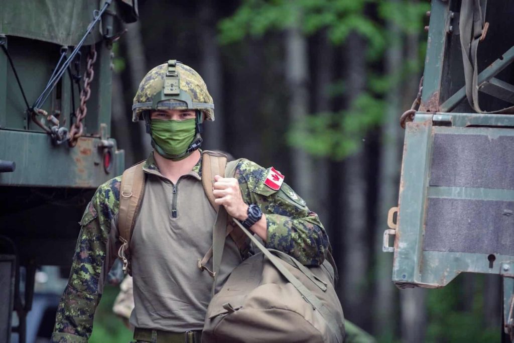 A soldier of the Department of National Defence of Canada is holding his backpack