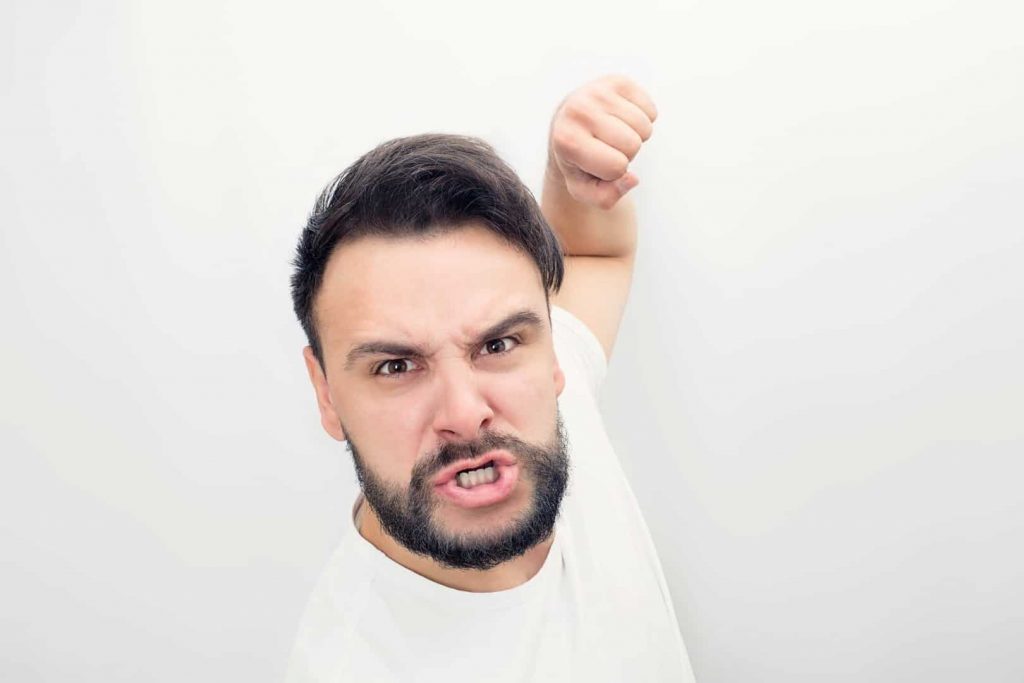 An angry white man is holding his fist, trying to hit